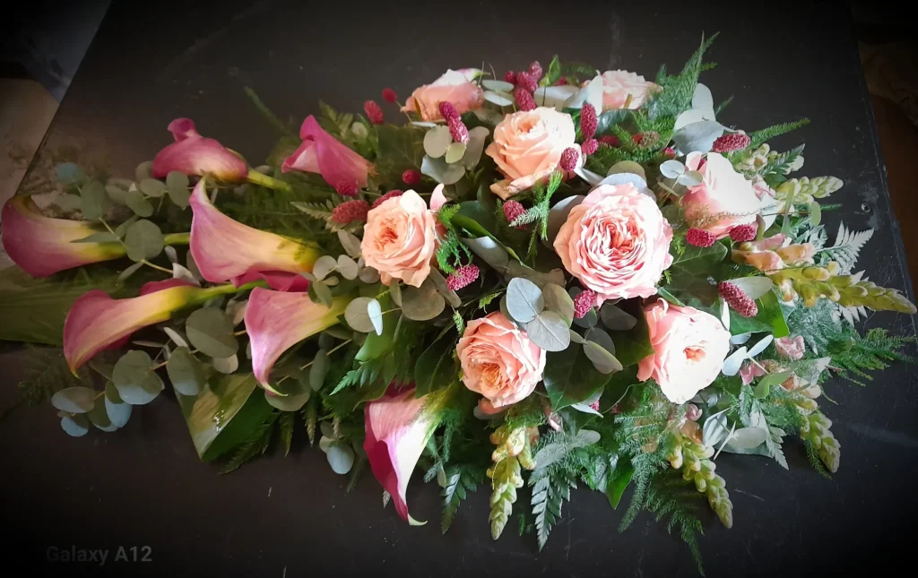Langwerpig rouwstuk met perzikkleurige rozen en roze calla's – Bloem en Atelier Floriante