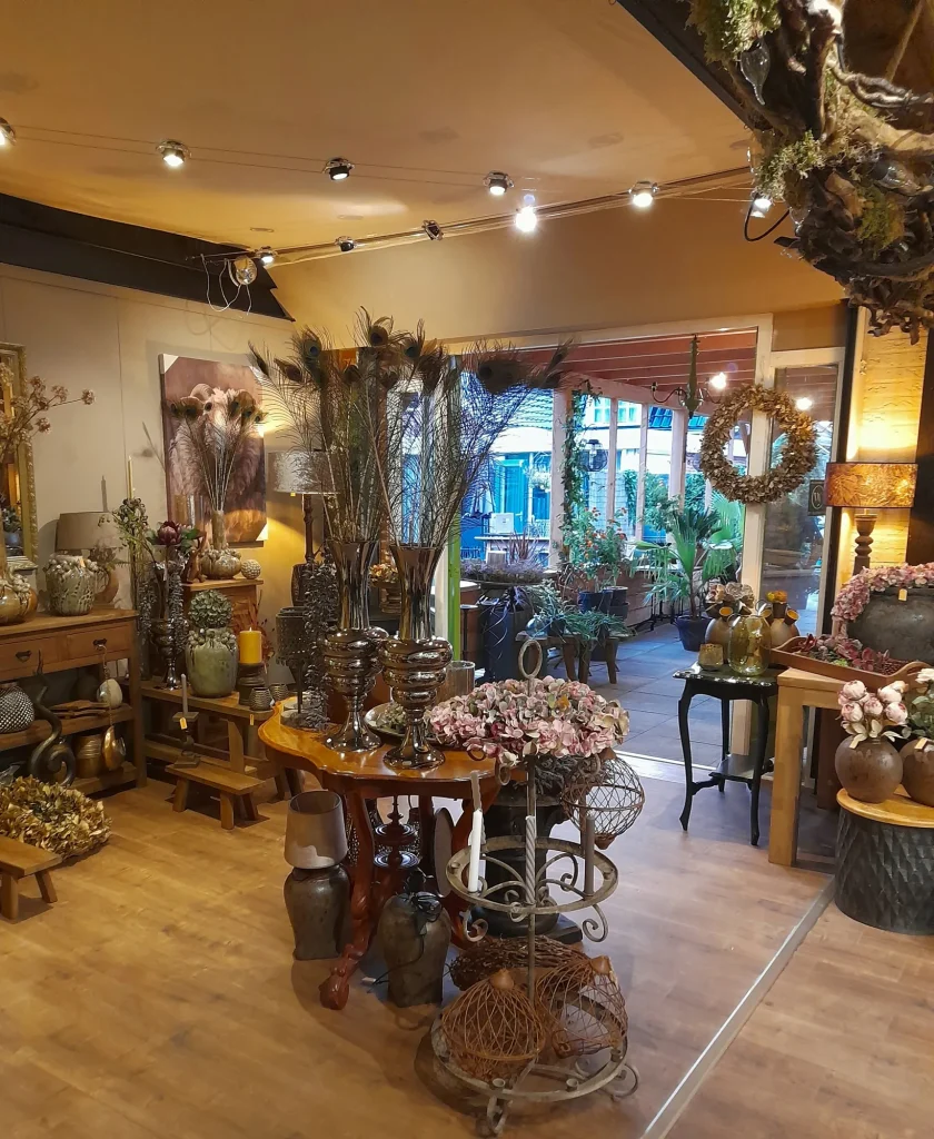 Winkel met houten tafels, decoratie en zicht op het terras – Bloem en Atelier Floriante
